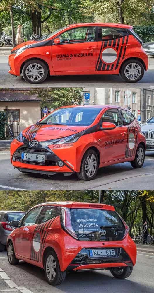 Orange and black Toyota wrap for Dūma un Vizbules, photographed from three angles on a city street