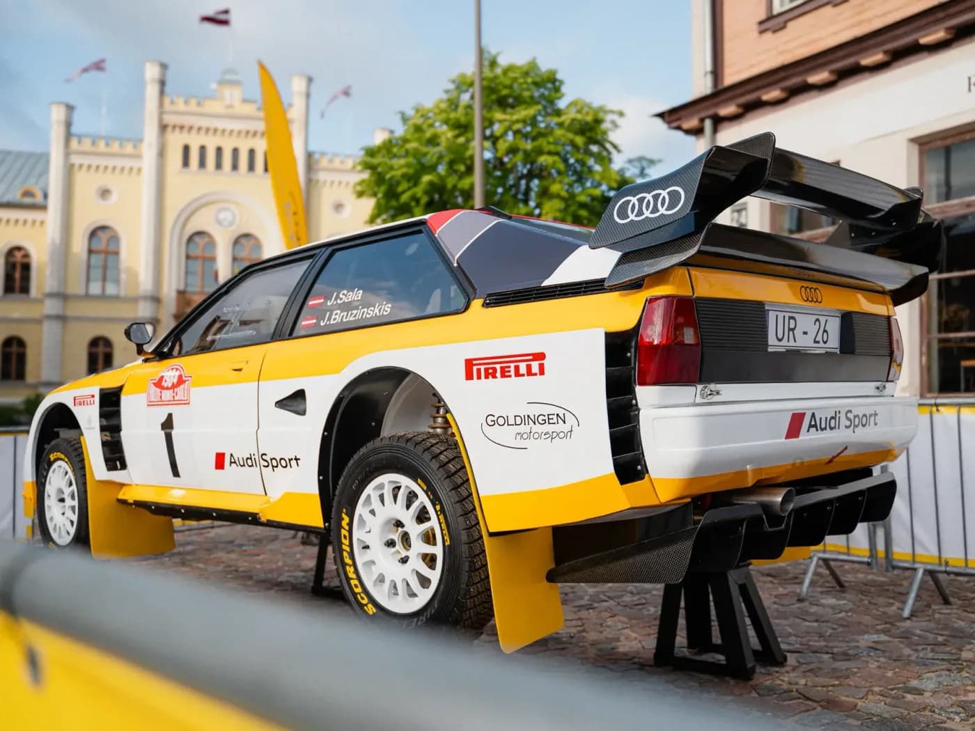 Oriģinālais foto Audi rallija auto aizmugurei ārpus vēsturiskas ēkas