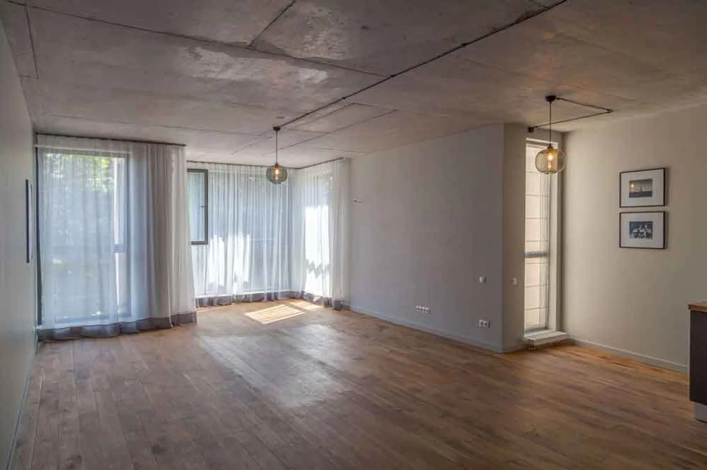 Gaiša loft dzīvojamā istaba ar atklātiem betona griestiem un griestu augstuma aizkariem