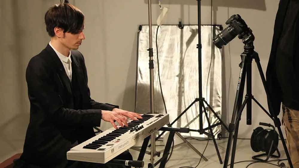 Musician playing a keyboard on a lit studio set