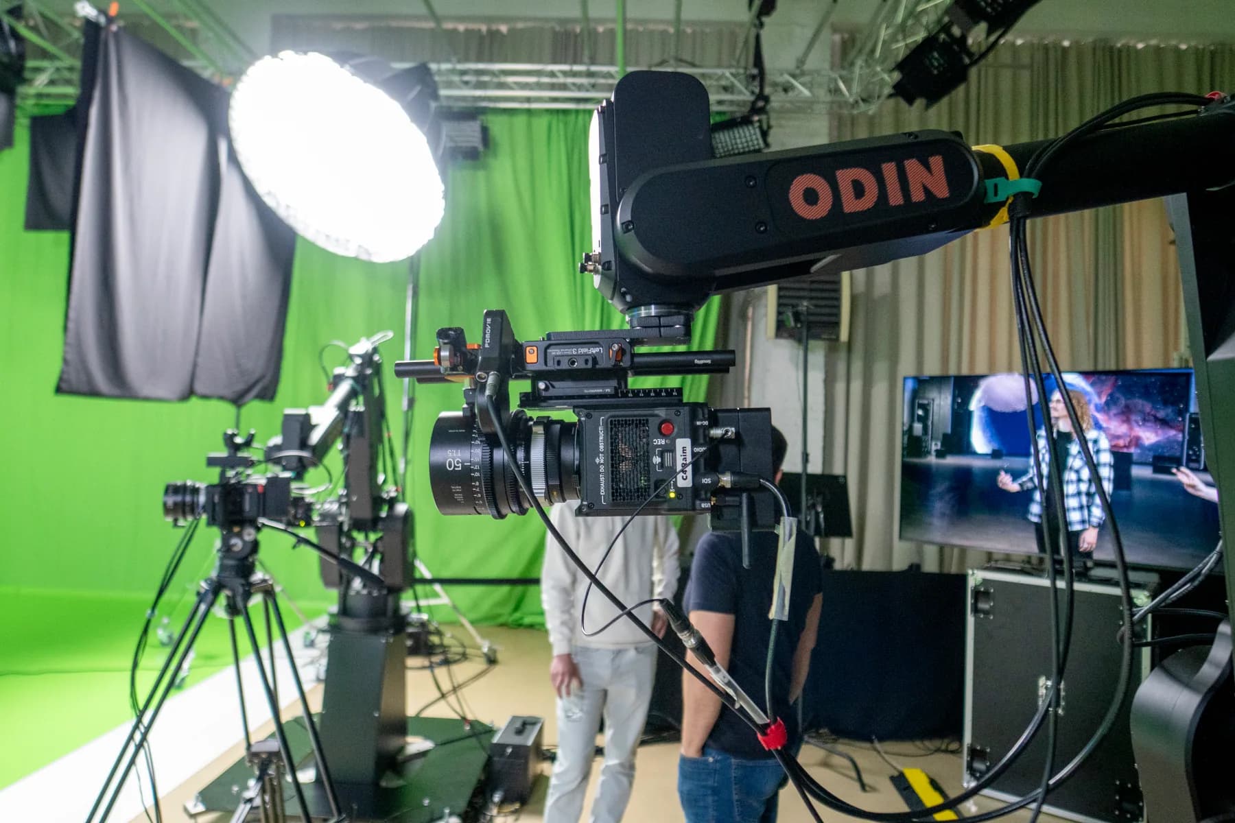 Crew reviewing a take on a monitor beside a robotic camera rig on a chromakey stage